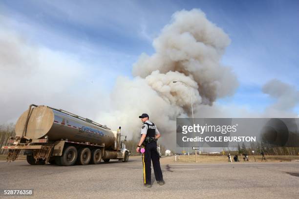 Police officer works a road block on Highway 63 near Fort McMurray, Alberta on May 6, 2016. - Canadian police led convoys of cars through the burning...