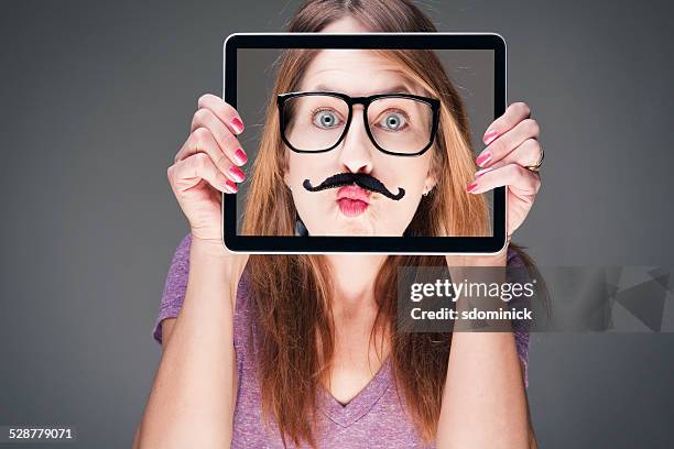 woman holding funny photo over face - hiding from selfie stockfoto's en -beelden