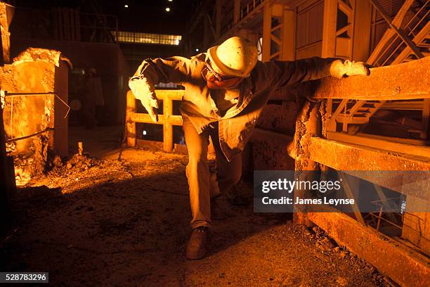 Man checks steel being poured at the Allegheny Ludlum Corporation in Pittsburgh, Pennsylvania.