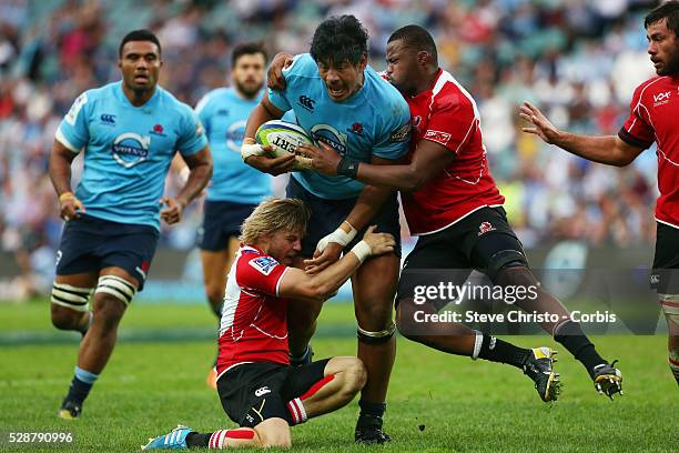 Waratahs Will Skelton is tackled by Lions scrumhalf Faf De Klerk and left lock Luvuyiso Lusaseni at Allianz Stadium. Sydney, Australia. Sunday 18th...