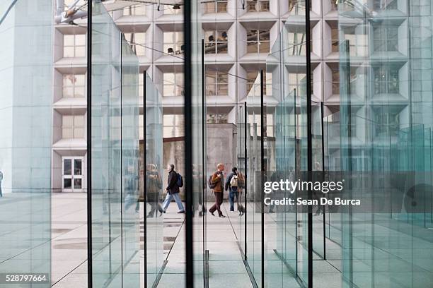 pedestrians walking past glass panels at la grande arche, paris, france - la grande arche de la défense stock-fotos und bilder