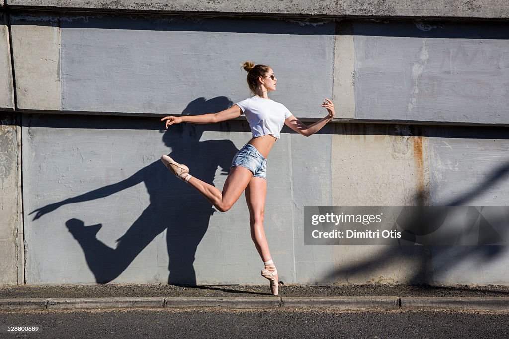 Ballerina leaping on sidewalk on points