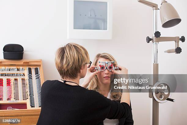optometrist performing a refraction in an optometrics store - eye exam stock pictures, royalty-free photos & images