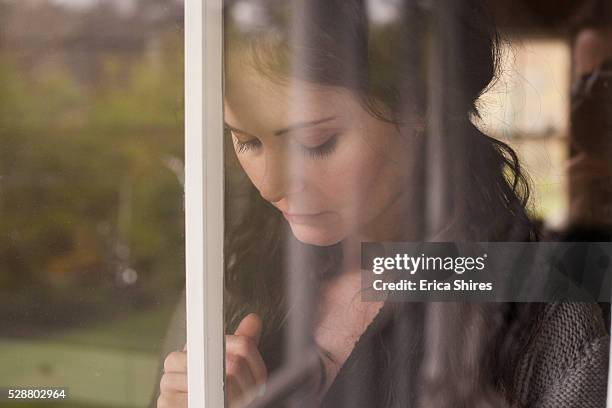 young woman at window - woman crying stock pictures, royalty-free photos & images