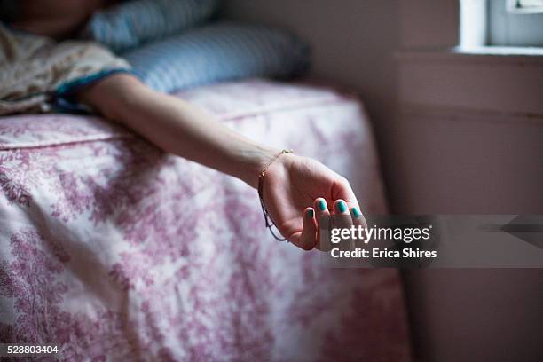 girl's arm hanging off bed - bewusteloos stockfoto's en -beelden