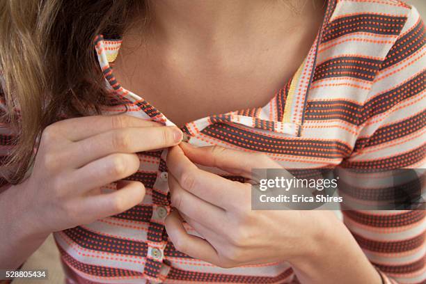 young woman buttoning striped shirt - buttoning shirt stockfoto's en -beelden