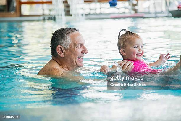 grandfather and granddaughter (12-23 months) in swimming pool - babyschwimmen stock-fotos und bilder