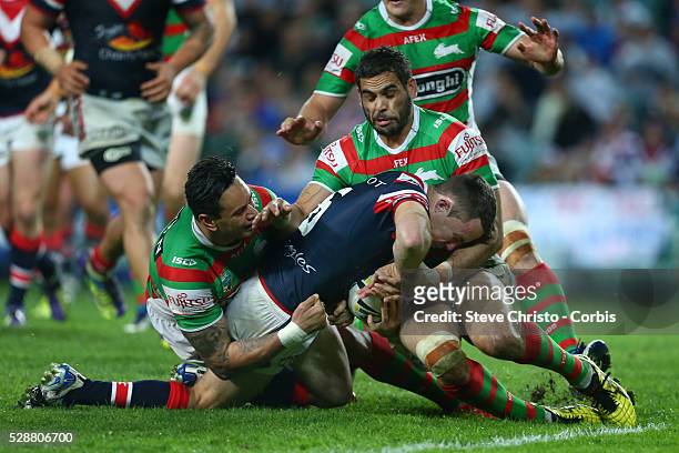 Roosters James Maloney is stopped short of the line by Rabbitohs John Sutton and Greg Inglis during the match at Allianz Stadium. Sydney, Australia....
