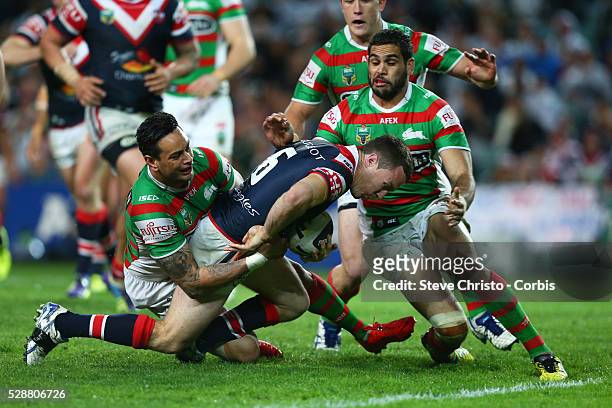 Roosters James Maloney is stopped short of the line by Rabbitohs John Sutton and Greg Inglis during the match at Allianz Stadium. Sydney, Australia....