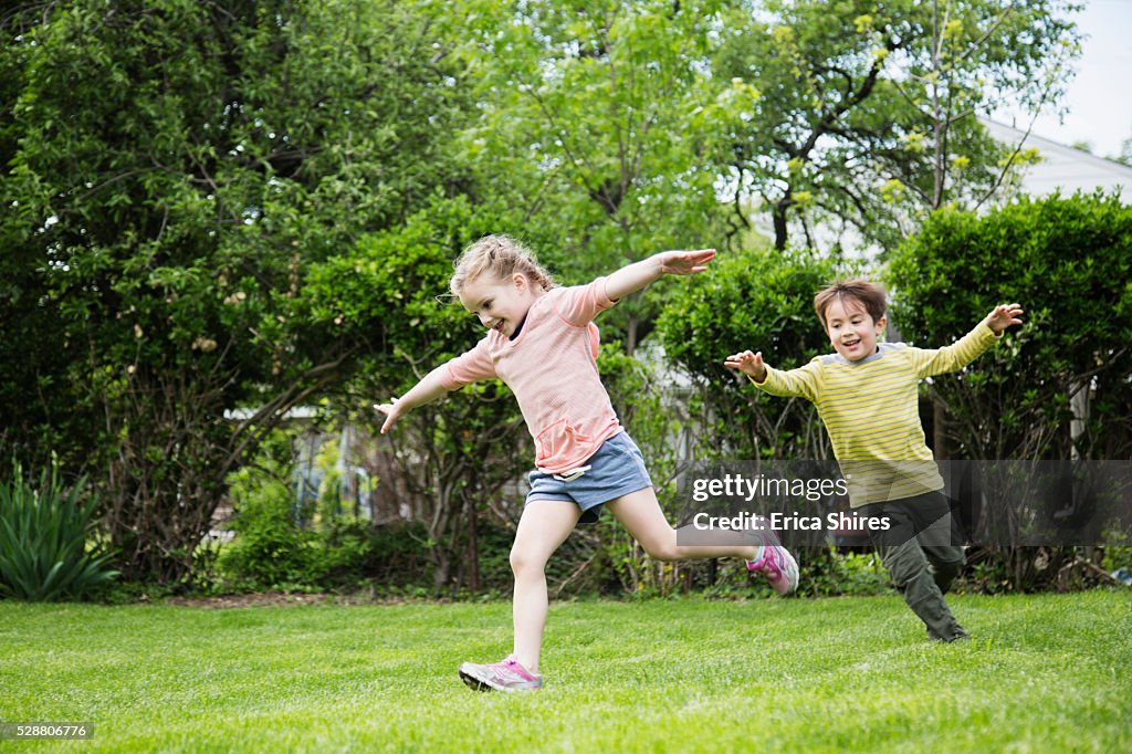 Siblings (4-5), (6-7) running in backyard