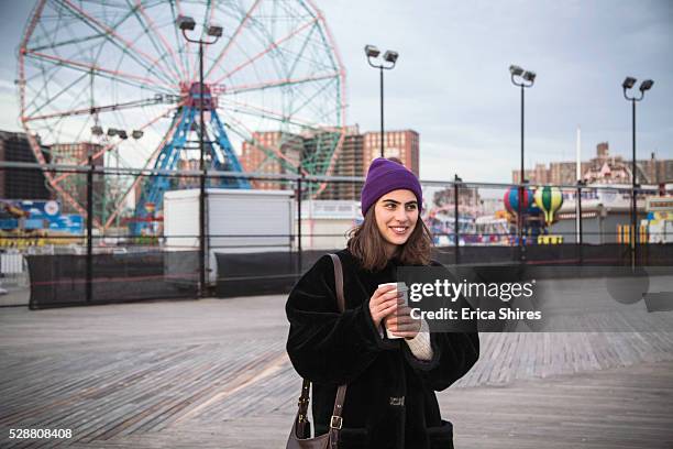 woman standing on boardwalk in front of closed amusement park - coney island stock pictures, royalty-free photos & images