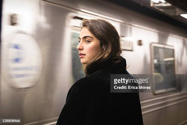 train arriving at station while woman waits - new york city subway stock-fotos und bilder