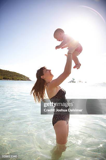 mother throwing baby girl in the air at the beach - dalsimer foto e immagini stock