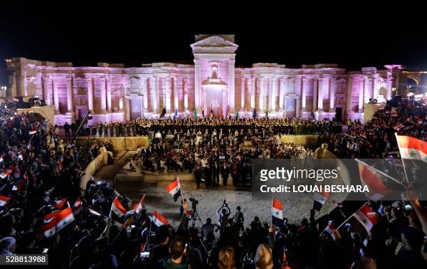 The audience waves Syrian flags as they attend a music concert in the ancient theatre of Syria's ravaged city of Palmyra on May 6 after Syrian troops...