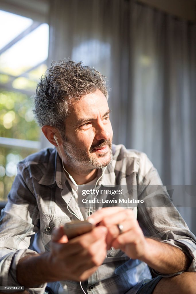 Man listening with earbuds on a mobile device