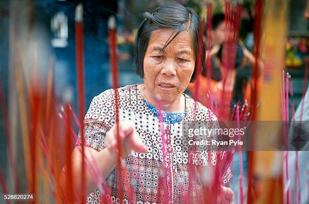 An elderly woman burns incense at the Nanputuo Temple in Xiamen. The Nanputuo Temple is located on the southeast of Xiamen Island. It is surrounded...
