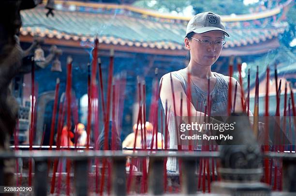 Woman burns incense at the Nanputuo Temple in Xiamen. The Nanputuo Temple is located on the southeast of Xiamen Island. It is surrounded by the...