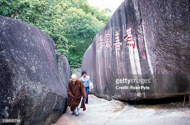Nun walks through a narrow rock pass on the mountain above the Nanputuo Temple in Xiamen. The Nanputuo Temple is located on the southeast of Xiamen...