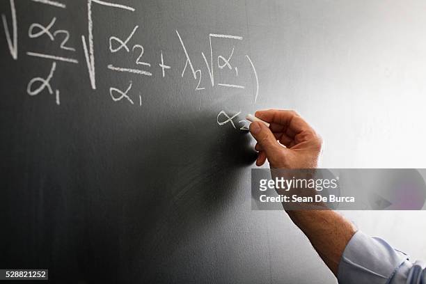teacher writing algebra equation on chalkboard - chalk hands stock pictures, royalty-free photos & images