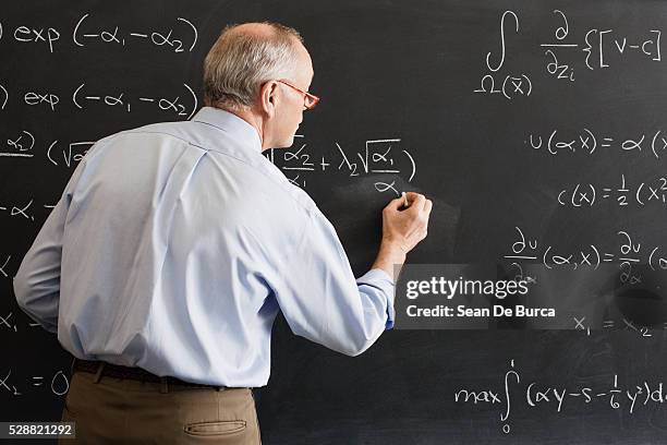 teacher writing algebra equation on chalkboard - orador fotografías e imágenes de stock