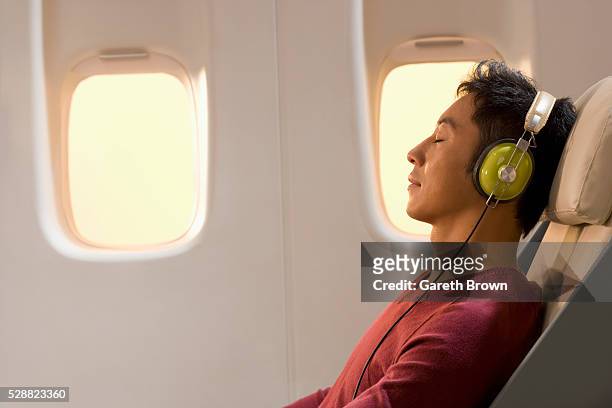 man resting and listening to music on airplane - airplane interior stockfoto's en -beelden