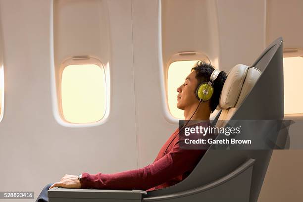 man resting and listening to music on airplane - comfortable flight stock pictures, royalty-free photos & images