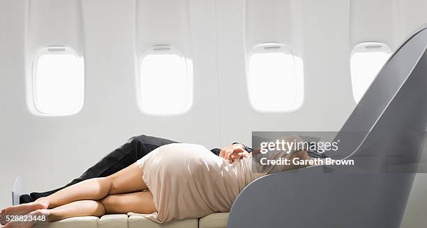couple sleeping in reclining chair on airplane - jet lag stockfoto's en -beelden