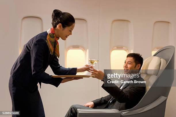 flight attendant serving man martini - flight attendants stock-fotos und bilder