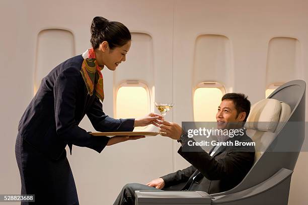 flight attendant serving man martini - crew foto e immagini stock