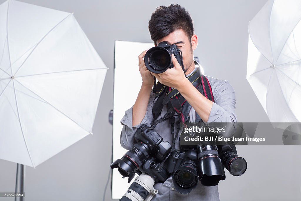 Photographer taking picture with many cameras hanging on his neck