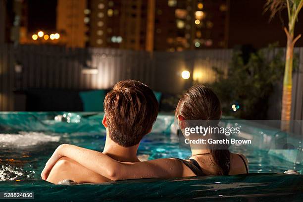 couple in rooftop hot-tub at night - hot tub stock pictures, royalty-free photos & images