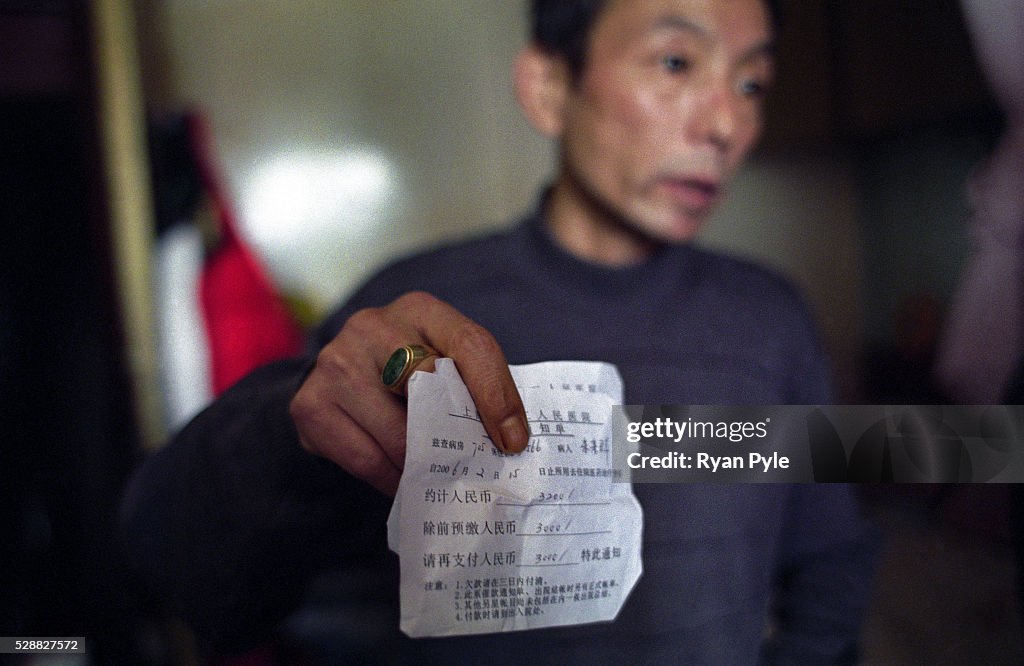 China - Shanghai - Healthcare - A Diabetic Stands Inside his Home Holds A Medical Bill