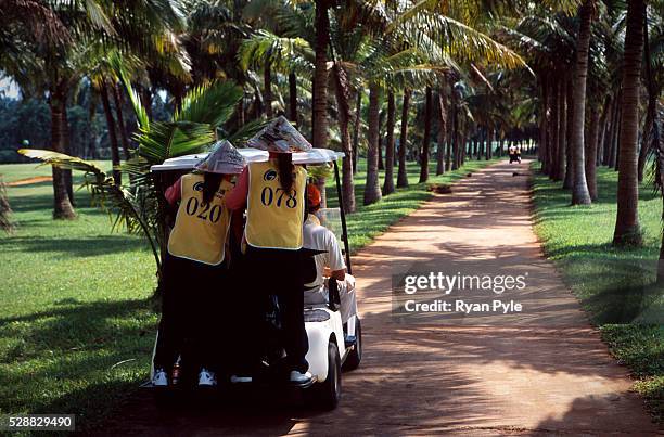 Caddies ride on the back of golf carts at the Taida Golf Course just outside Haikou city, the capital of Hainan province in China. Taida Golf Course...