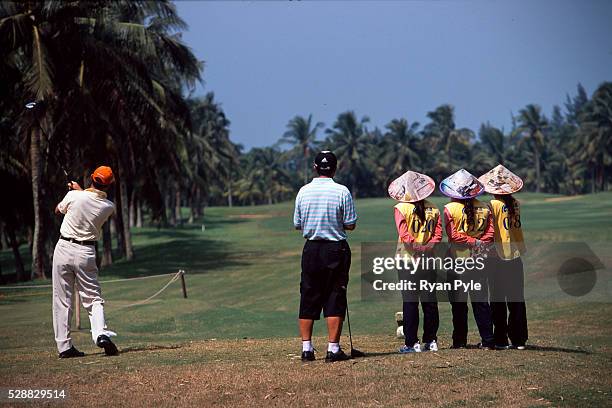 Caddies watch their golfers tee off at the Taida Golf Course just outside Haikou city, the capital of Hainan province in China. Taida Golf Course...