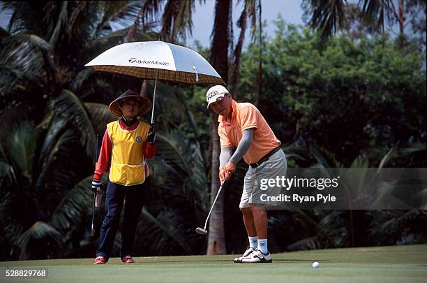 Caddy holds an umbrella as a golfer watching his put at the Taida Golf Course just outside Haikou city, the capital of Hainan province in China....