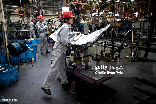 Worker lifts a steel beam that has just come off the assembly line at the CAMC heavy-duty truck factory in Maahshan, China.