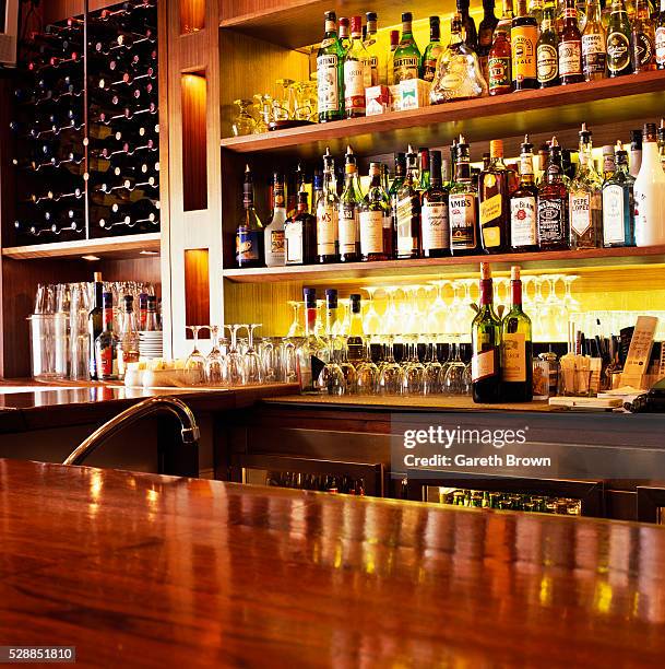 liquor bottles sitting on shelves - kneipe stock-fotos und bilder