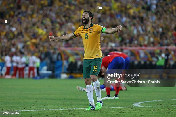 Australia's captain Mile Jedinak stands with both arms stretched after the referee blew his whistle to signal the end of the match and Australia...