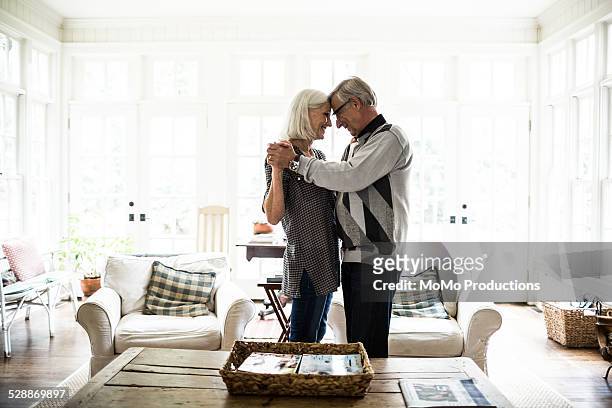 senior couple dancing in living room - coppia anziana foto e immagini stock