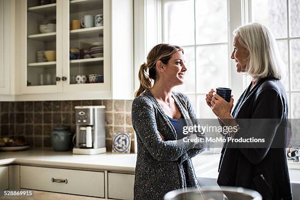 mother and daughter having coffee in kitchen - mom arms crossed stock pictures, royalty-free photos & images