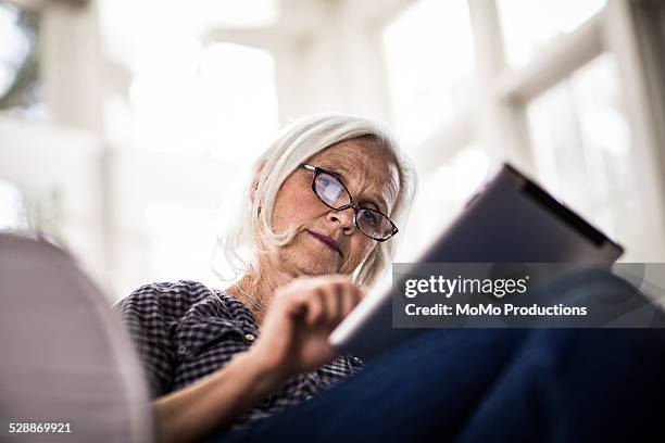 senior woman using tablet - red blouse fotografías e imágenes de stock