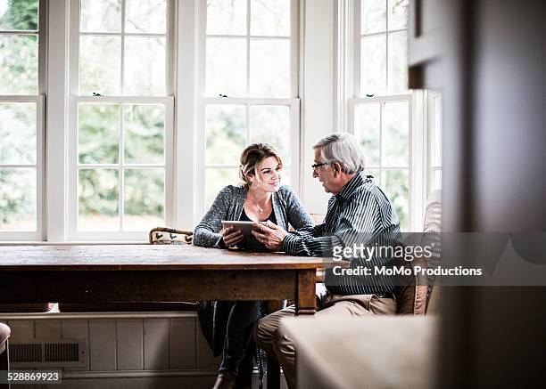father and daughter using tablet - senior adult stock-fotos und bilder