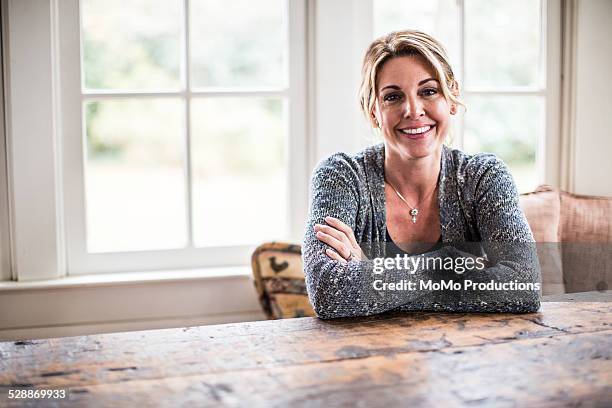 portrait of woman at home - sitting at table looking at camera stock-fotos und bilder