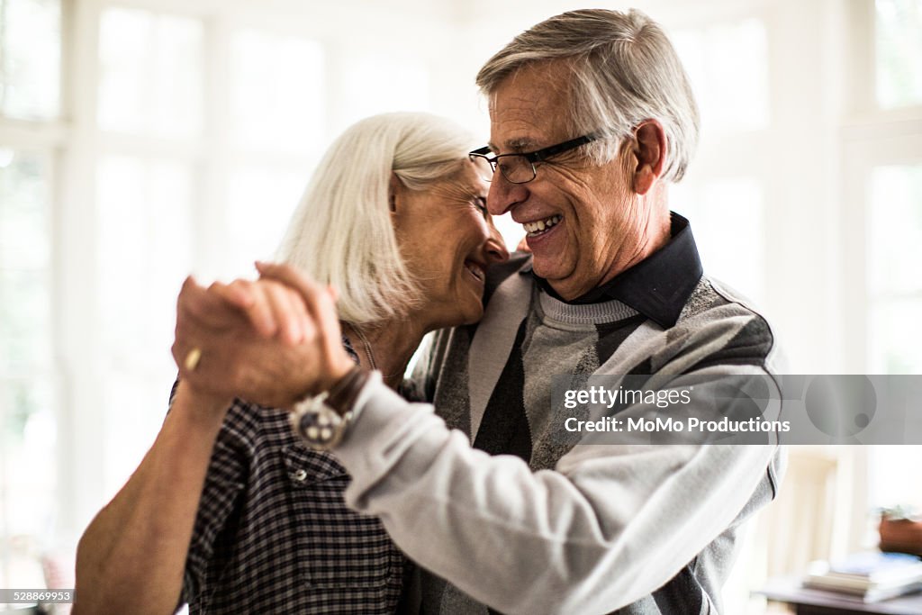 Senior couple dancing in living room