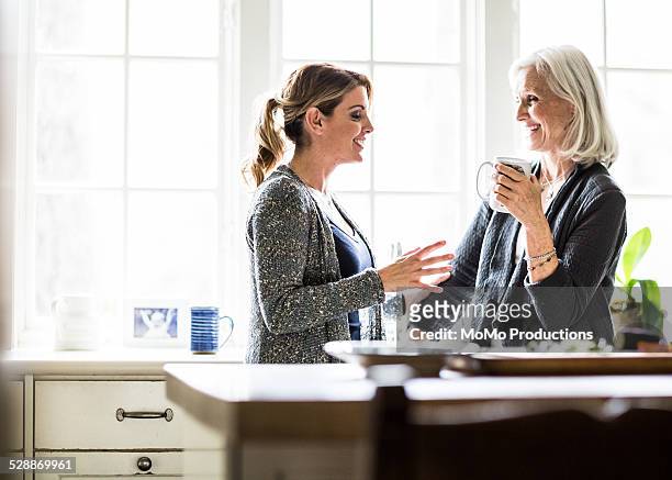 mother and daughter having coffee in kitchen - mother daughter kitchen stock-fotos und bilder