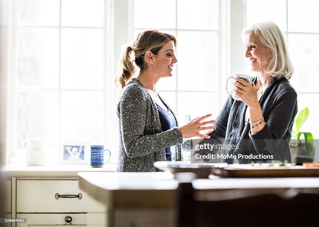 Mother and daughter having coffee in kitchen