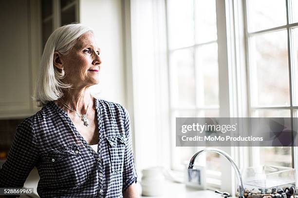 portrait of senior woman in kitchen - só uma mulher idosa imagens e fotografias de stock