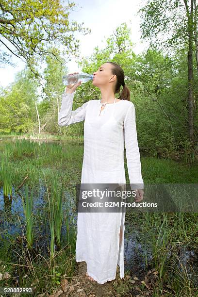 young woman drinking water from bottle - see through negligee stock-fotos und bilder