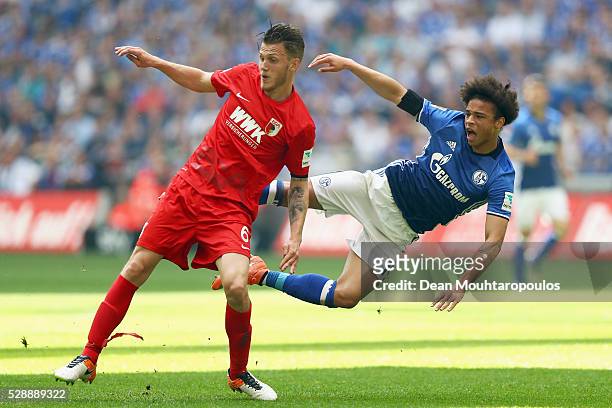 Leroy Sane of Schalke is tackled and stopped by Jeffrey Gouweleeuw of FC Augsburg during the Bundesliga match between FC Schalke 04 and FC Augsburg...