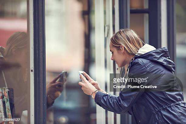 woman taking a photo with smartphone - store window stock pictures, royalty-free photos & images